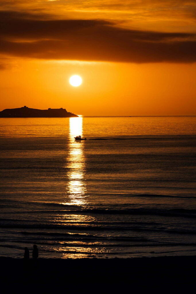 A fisherman returns back to port as the sun sets behind Porthgwidden Beach as near Hayle, Cornwall
